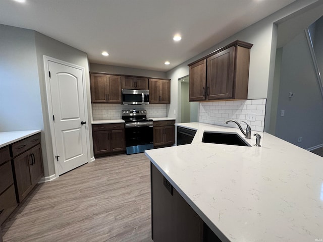 kitchen with sink, light hardwood / wood-style floors, stainless steel appliances, light stone countertops, and dark brown cabinets