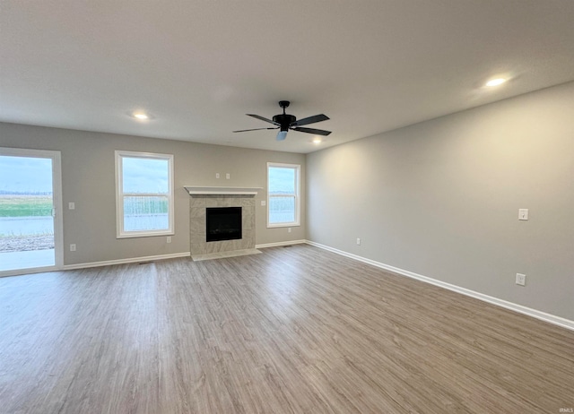 unfurnished living room featuring hardwood / wood-style flooring, ceiling fan, and a fireplace