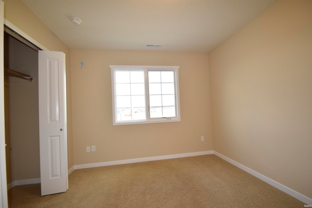 unfurnished bedroom with light carpet and a closet