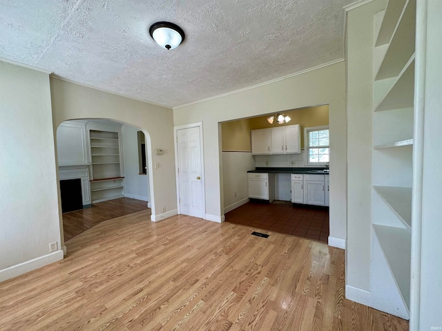 unfurnished living room with ornamental molding, sink, light tile floors, and a textured ceiling