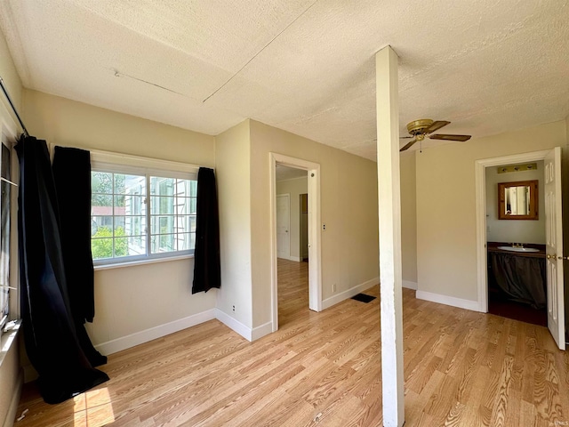 unfurnished bedroom with sink, light hardwood / wood-style flooring, ceiling fan, and a textured ceiling