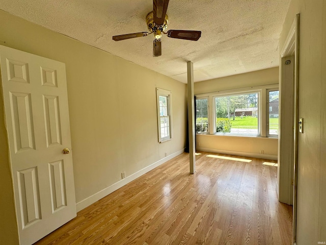 empty room featuring light hardwood / wood-style flooring, ceiling fan, and a textured ceiling