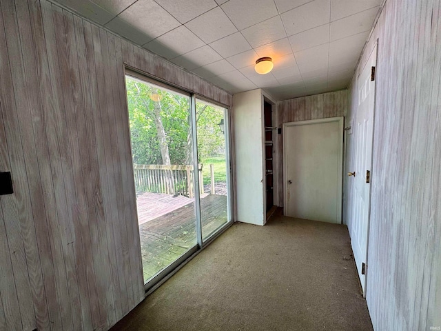 unfurnished room featuring carpet and wooden walls