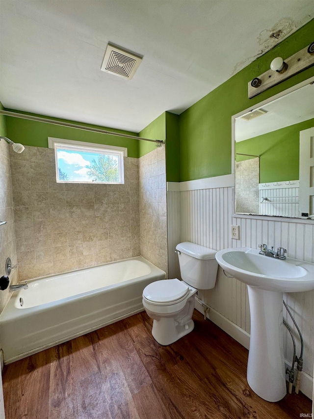 bathroom featuring tiled shower / bath combo, toilet, and hardwood / wood-style flooring