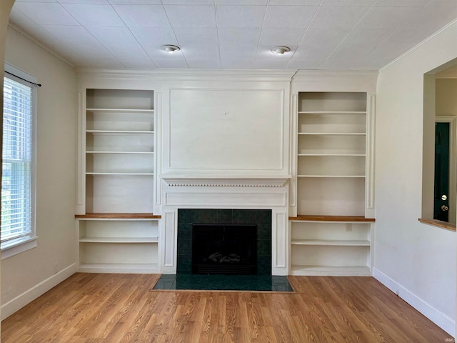 unfurnished living room with light hardwood / wood-style flooring, a fireplace, and built in features