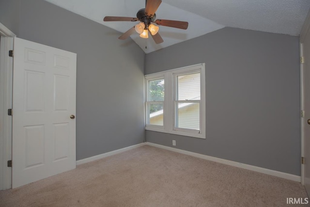 spare room featuring ceiling fan, vaulted ceiling, carpet, and a textured ceiling