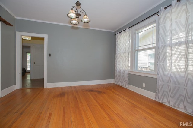 empty room with ornamental molding, wood-type flooring, and a chandelier