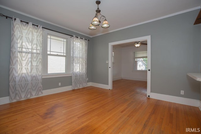 spare room with ceiling fan with notable chandelier, plenty of natural light, light wood-type flooring, and ornamental molding