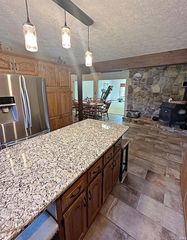 kitchen with hanging light fixtures, a textured ceiling, stainless steel refrigerator with ice dispenser, and light stone countertops