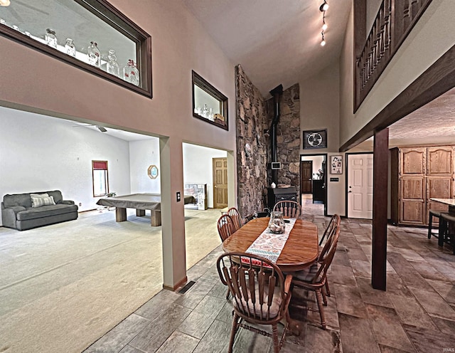 tiled dining space featuring high vaulted ceiling, rail lighting, a wood stove, and billiards