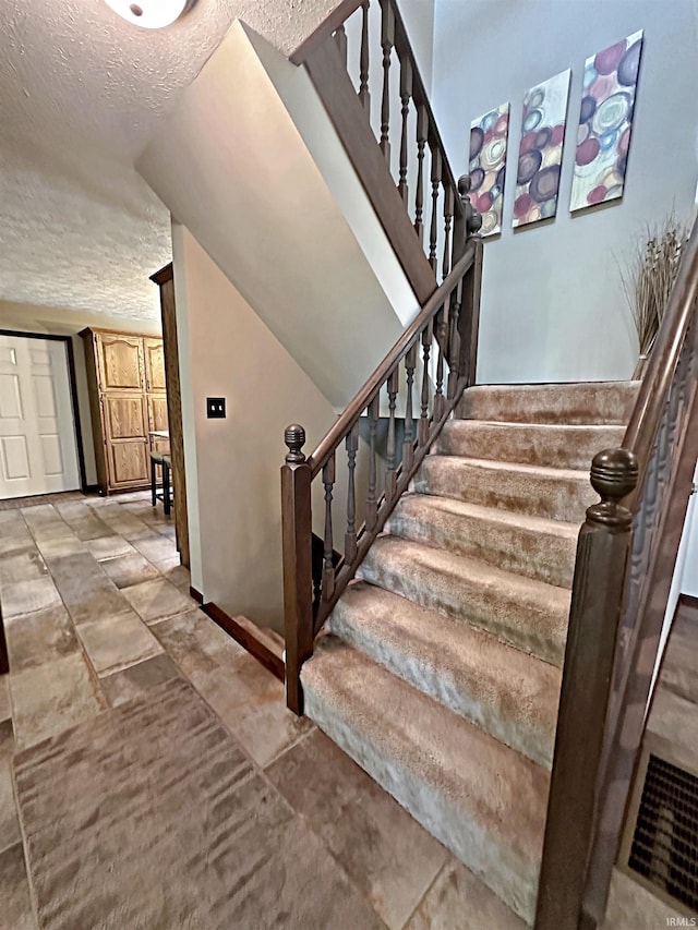 staircase with tile flooring and a textured ceiling