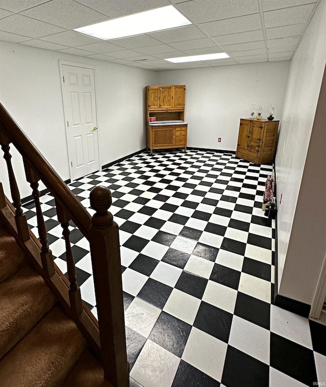 interior space with a drop ceiling and dark tile flooring