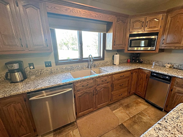 kitchen with stainless steel appliances, light tile floors, sink, and light stone countertops