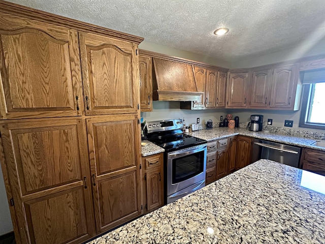 kitchen featuring a textured ceiling, custom range hood, stainless steel appliances, and light stone countertops