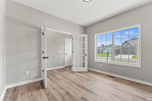 empty room featuring french doors and light hardwood / wood-style flooring