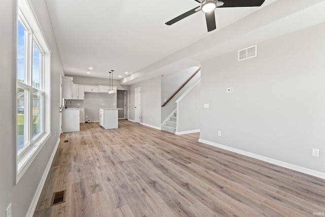 unfurnished living room featuring ceiling fan, sink, and light hardwood / wood-style flooring