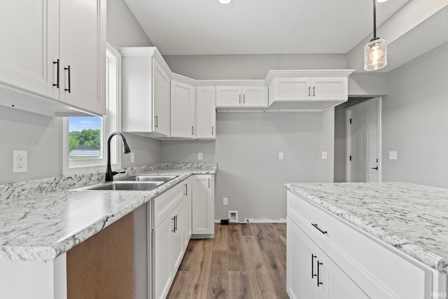 kitchen featuring light stone countertops, hardwood / wood-style floors, pendant lighting, sink, and white cabinetry