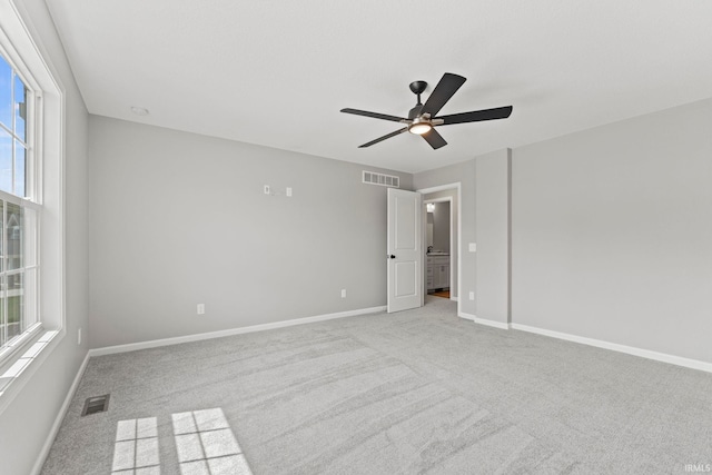 carpeted empty room with ceiling fan and a wealth of natural light