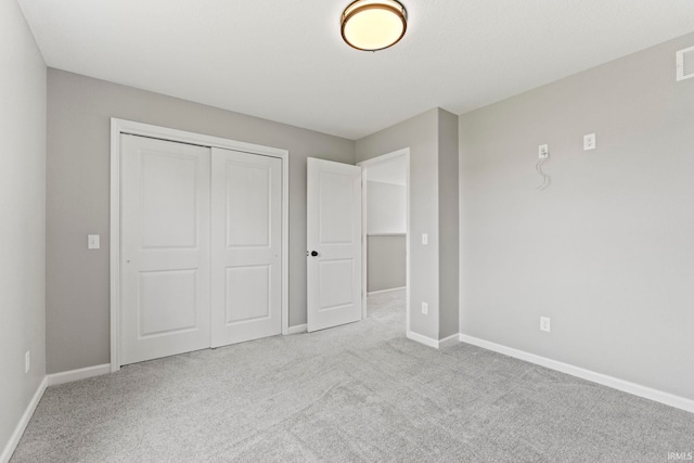 unfurnished bedroom with light carpet and a closet