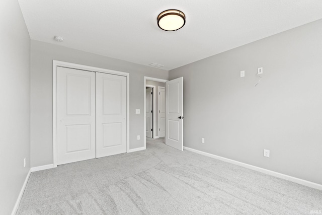 unfurnished bedroom featuring light carpet and a closet