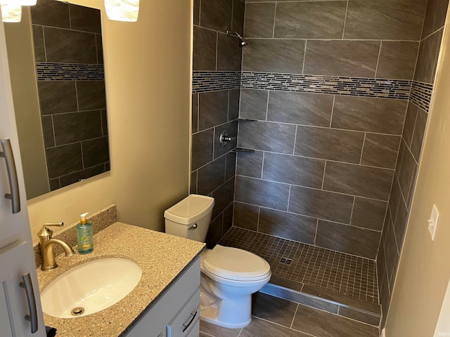 bathroom featuring vanity, toilet, and a tile shower