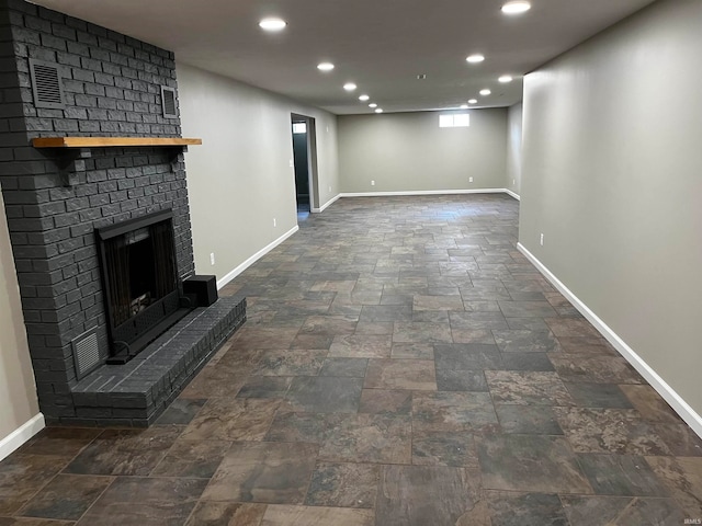 unfurnished living room with dark tile floors, brick wall, and a brick fireplace