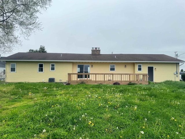 rear view of house with central AC, a wooden deck, and a lawn