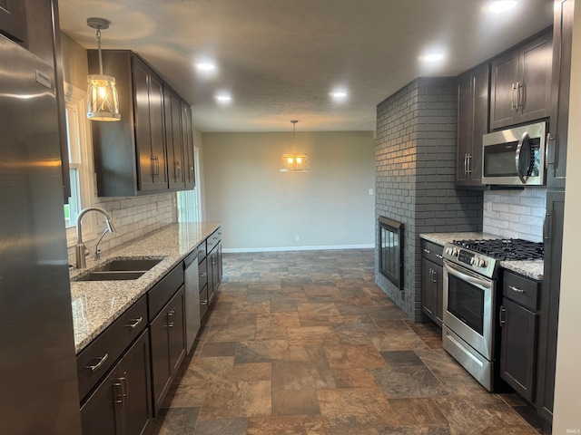 kitchen featuring pendant lighting, stainless steel appliances, sink, light stone counters, and tasteful backsplash