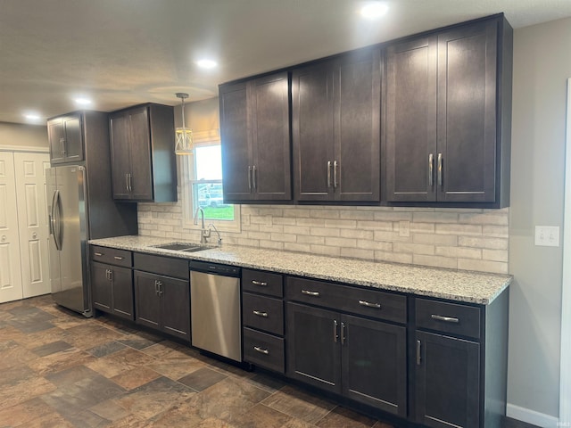 kitchen featuring light stone countertops, appliances with stainless steel finishes, backsplash, hanging light fixtures, and sink