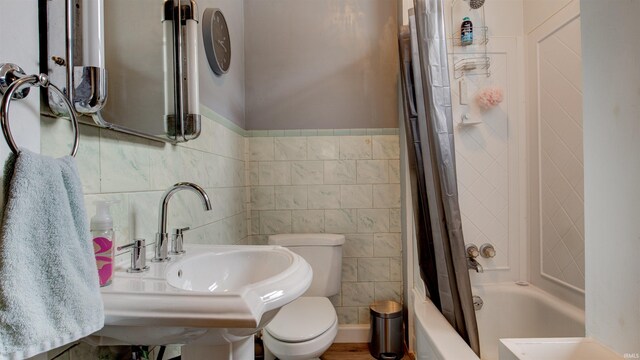 bathroom featuring tile walls, toilet, and shower / tub combo with curtain