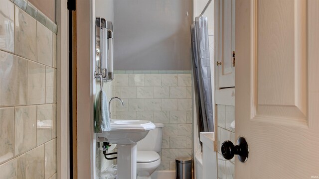 bathroom featuring tile walls and toilet