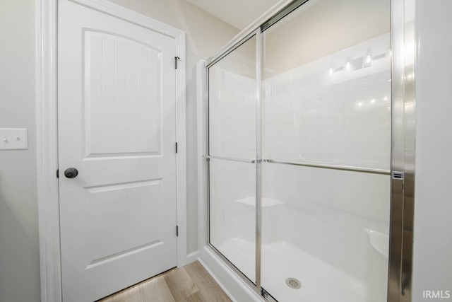 bathroom featuring a shower with door and wood-type flooring