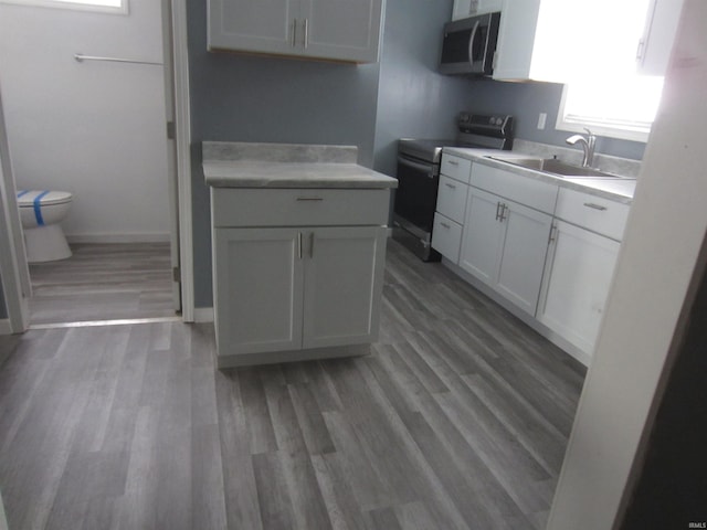 kitchen featuring range with electric cooktop, wood-type flooring, white cabinetry, and sink