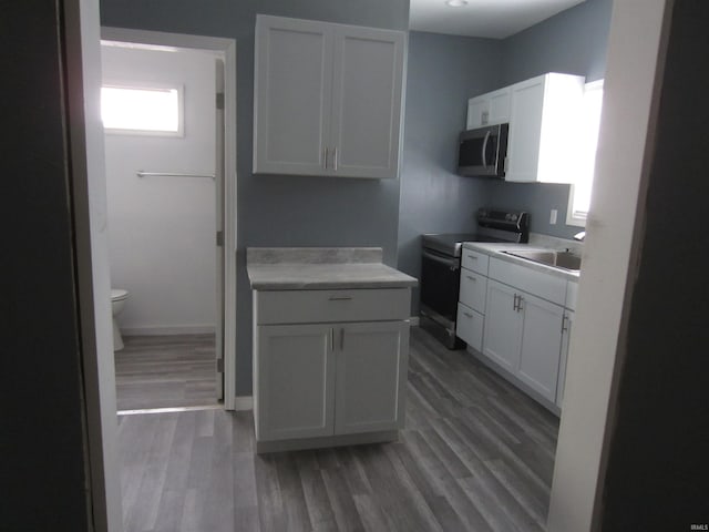 kitchen with hardwood / wood-style floors, sink, white cabinetry, and electric range oven