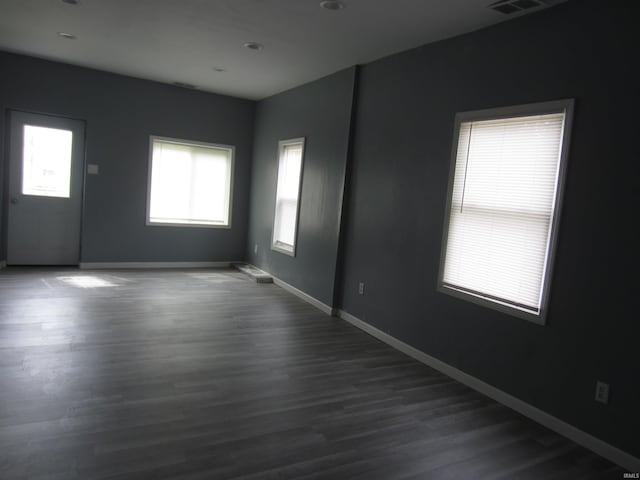 empty room featuring plenty of natural light and dark wood-type flooring