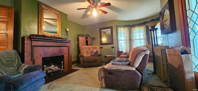 sitting room with a fireplace, carpet flooring, radiator heating unit, ceiling fan, and a textured ceiling