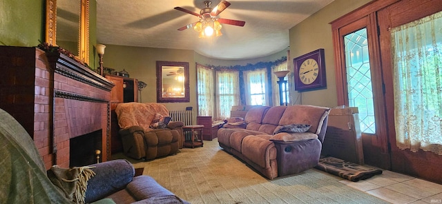 tiled living room featuring a wealth of natural light, radiator, ceiling fan, and a fireplace