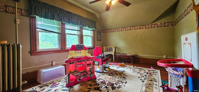 rec room with hardwood / wood-style flooring, radiator, ceiling fan, and vaulted ceiling