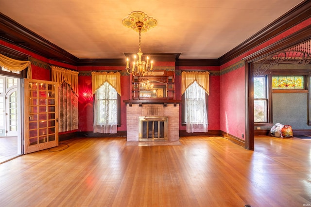 unfurnished living room featuring crown molding, hardwood / wood-style flooring, a wealth of natural light, and a brick fireplace