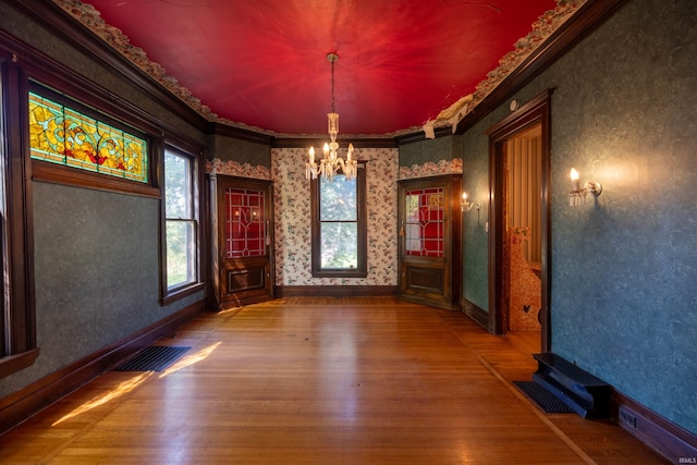 unfurnished room featuring dark hardwood / wood-style flooring, a notable chandelier, and ornamental molding