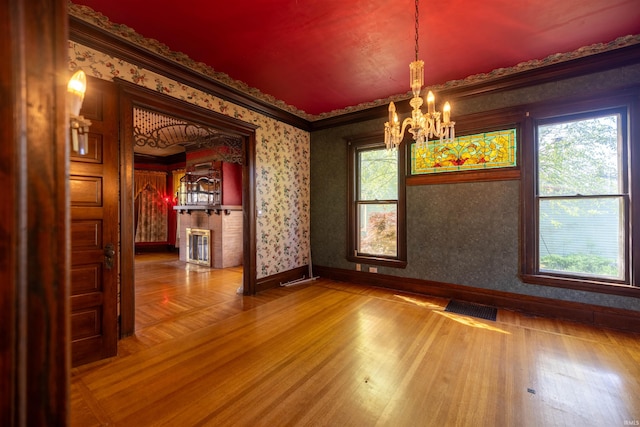 empty room with hardwood / wood-style floors, a chandelier, and a wealth of natural light