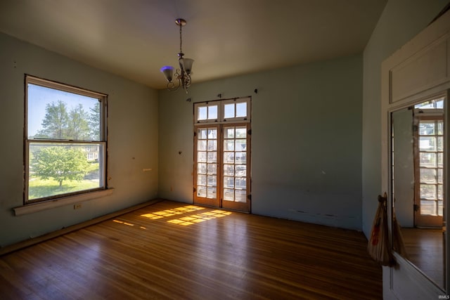 spare room featuring an inviting chandelier and dark wood-type flooring