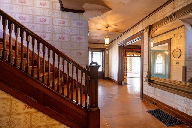 entrance foyer featuring brick wall, ornamental molding, and wood-type flooring