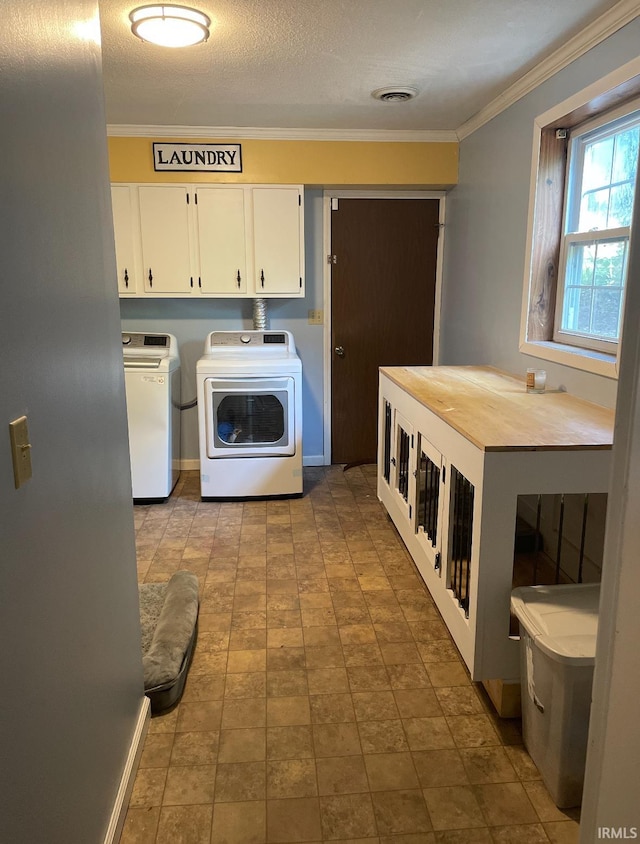 laundry room featuring cabinets, a textured ceiling, washer and clothes dryer, and ornamental molding