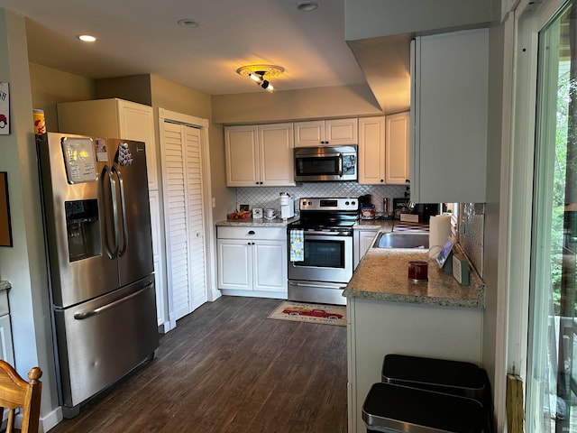 kitchen featuring backsplash, white cabinetry, stainless steel appliances, and dark wood-type flooring