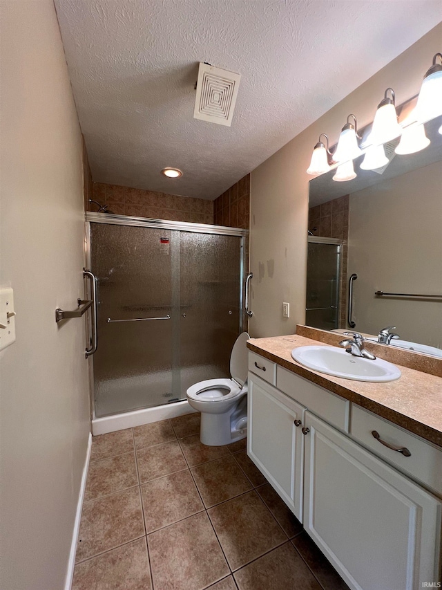 bathroom featuring tile flooring, large vanity, a textured ceiling, toilet, and a shower with shower door