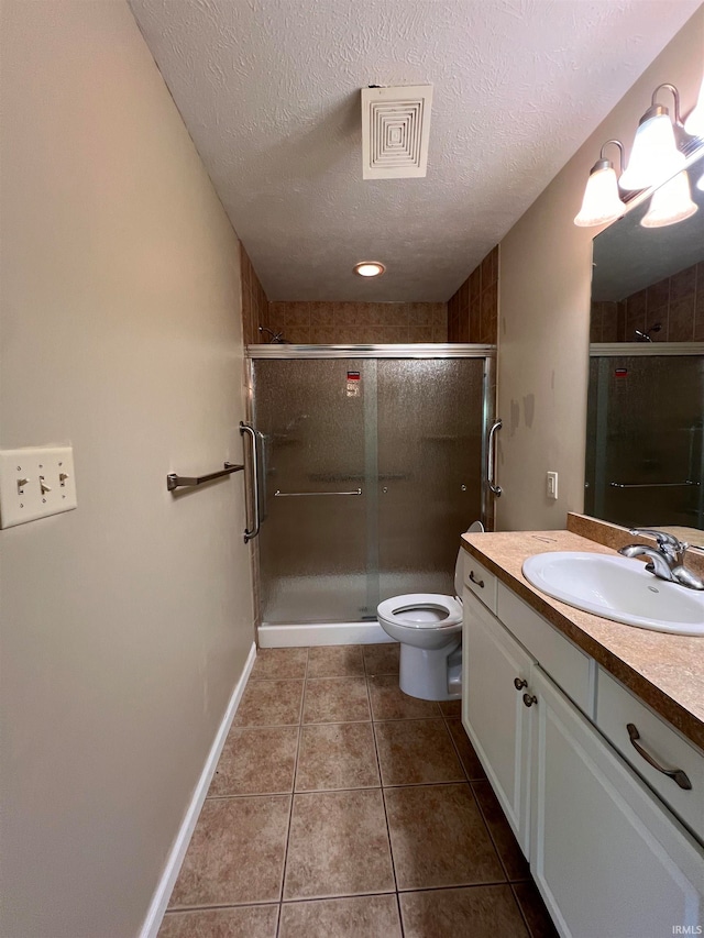 bathroom featuring vanity, toilet, tile floors, and a textured ceiling