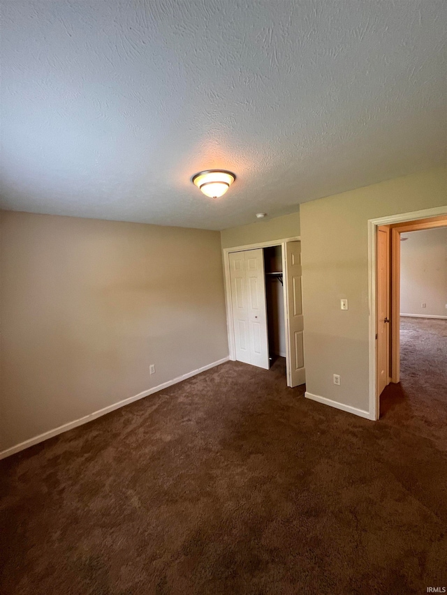 unfurnished bedroom with a closet, a textured ceiling, and dark carpet