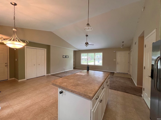 kitchen featuring hanging light fixtures, lofted ceiling, light tile floors, and white cabinetry