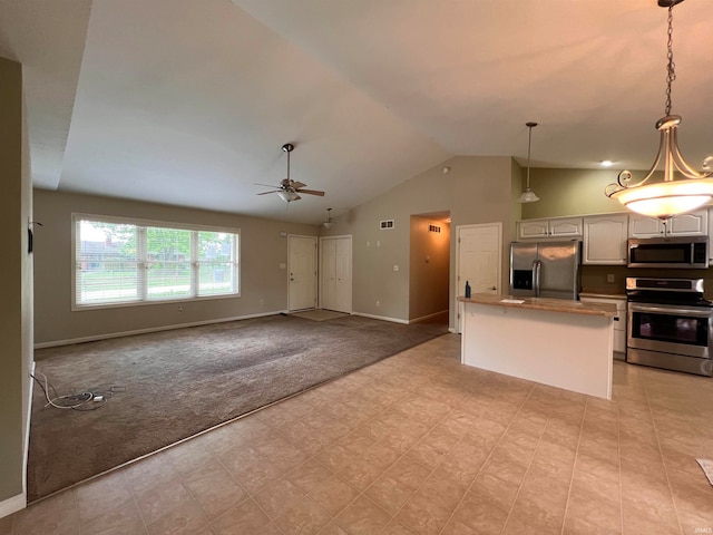 kitchen with appliances with stainless steel finishes, a center island, white cabinets, light colored carpet, and hanging light fixtures